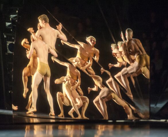 A male dancer picks up his female counterpart  as their image is projected into the mirror set